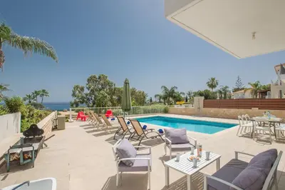 a patio with a pool and chairs and a table at Protaras Mesogeios Villa Me16 Beachfront Villa in Protaras Center in Protaras