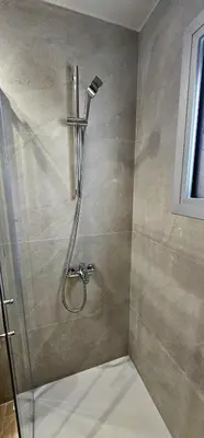 a shower with a shower head in a bathroom at Trendy Neapolis Beach Apartment in Limassol