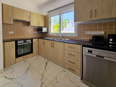 a kitchen with marble counter tops and a window at Nissi beach villa Azure in Ayia Napa