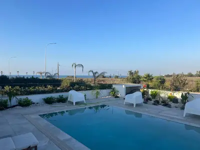 a swimming pool with two white chairs and a table at Nadine sea side villas in Larnaka