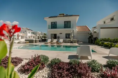 a villa with a swimming pool and a house at Nadine sea side villas in Larnaka