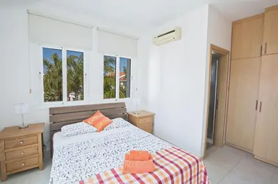a white bedroom with a bed and two windows at Protaras Holiday Villa Me25 in Protaras