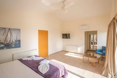 a bedroom with a bed and a table and a chair at Ayia Napa Holiday Villa At26 in Ayia Napa