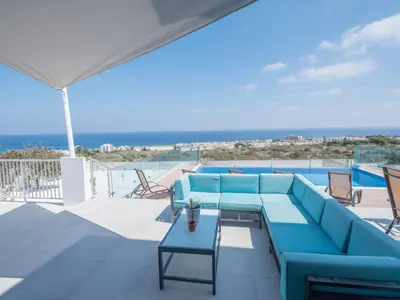 a blue couch and table on a patio with the ocean at Villa Clea,stunning 4bdr Protaras Villa, Seaviews in Protaras
