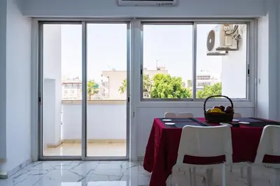 a dining room with a table and chairs and windows at Central & Cozy Larnaca Suite in Larnaka