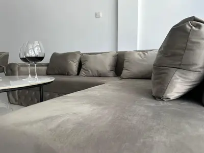 a couch with a pillow and a glass of wine on a table at Home For You - Holiday Apt Larnaca in Larnaka