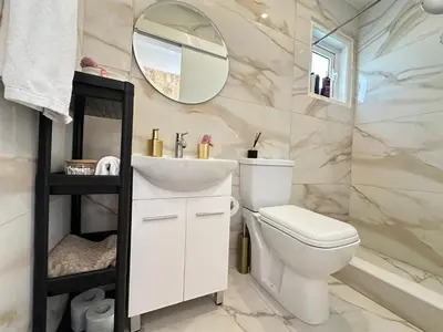 a bathroom with a white toilet and a mirror at Home For You - Holiday Apt Larnaca in Larnaka