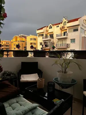 a balcony with a couch and a table and buildings at Makenzy 2 Bedrooms Apartment for rent in Larnaka