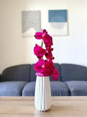 a white vase with pink flowers on a table at Sunrise Palette Suites in Larnaka