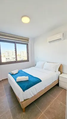 a bedroom with a large bed with two towels on it at Beachside Breeze Apartment in Larnaka