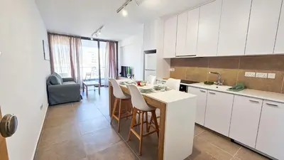 a kitchen with white cabinets and a table and chairs at Beachside Breeze Apartment in Larnaka