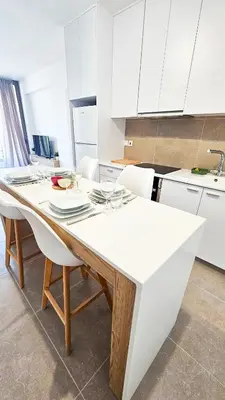 a kitchen with a white table and white cabinets at Beachside Breeze Apartment in Larnaka