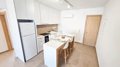 a kitchen with a white refrigerator and a table at Beachside Breeze Apartment in Larnaka