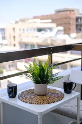a plant on a table with two cups on a balcony at The Serene Suite in Larnaka