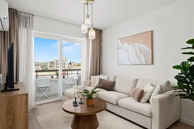 a living room with a white couch and a large window at The Serene Suite in Larnaka