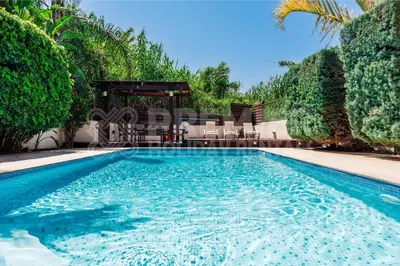 a swimming pool with chairs and a gazebo at Villa Coral in Paralimni