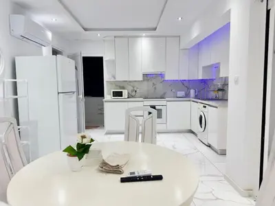 a white kitchen with a white table and chairs at Lumière Retreat 2 in Larnaka