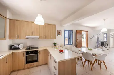 a kitchen with wooden cabinets and a table and chairs at Protaras Seaside Villa Protamare 32 in Protaras