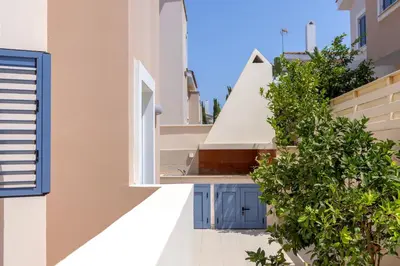 a building with blue doors and a green bush at Protaras Seaside Villa Protamare 32 in Protaras
