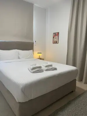 a bedroom with a large bed with white sheets at Kroisou Comfort Stay 2 BEDROOM in Ayios Dhometios