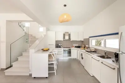 a kitchen with white cabinets and a sink and stairs at SeaSalt Villa in Paralimni