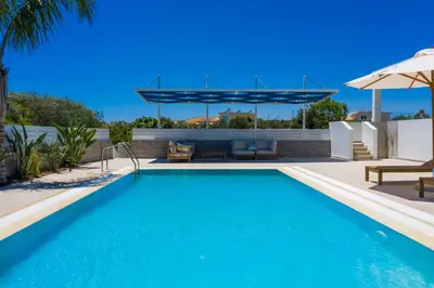 a swimming pool with a patio and an umbrella at Pantio Living Villa in Ayia Napa