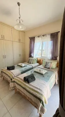 two beds in a room with purple curtains at Villa Porta Aurea in Ayia Napa