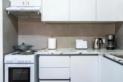a kitchen with white cabinets and a stove top oven at Destiny 1-Bedroom Apartment in Larnaka