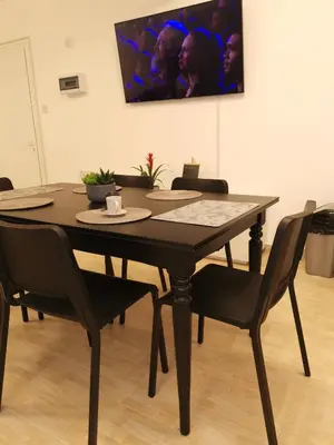 a dining room table with black chairs and a tv at Kennedy 5 apartman Ayia Napa in Ayia Napa