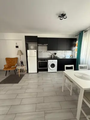a kitchen with black cabinets and a white appliance at Kypa rooms 50 steps to the beach in Larnaka
