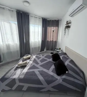 a bedroom with a bed with a black and white comforter at Kypa rooms 50 steps to the beach in Larnaka
