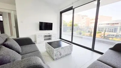 a living room with a couch and a tv at Poolside Lux Apartment in Larnaka