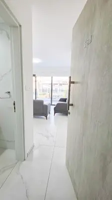 an open door in a white room with couches at Poolside Lux Apartment in Larnaka