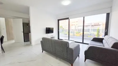 a living room with two couches and a large window at Poolside Lux Apartment in Larnaka