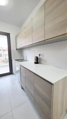 a kitchen with wooden cabinets and a tea kettle on the counter at Poolside Lux Apartment in Larnaka