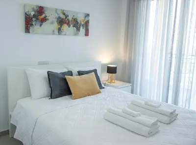 a large white bed with three pillows on it at Stylish Modern City Center Stay in Nicosia