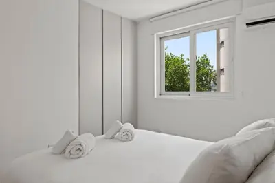 a white bedroom with a bed with towels on it at Themelio Living 2-Bed Apartment Nicosia City Centre in Nicosia