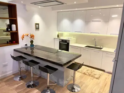 a kitchen with a large black counter and stools at Luxury Limassol Seaside Pool Suite in Limassol