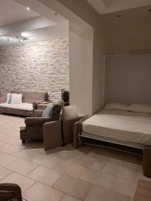 a bedroom with a bed and chairs and a brick wall at Sandy Kisses in Larnaka