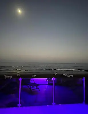 a pool with a view of the ocean at night at Sandy Kisses in Larnaka