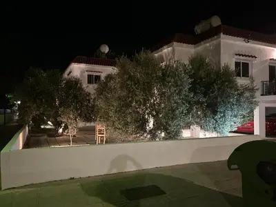 a white house with trees in front of it at night at Teak Charm in Larnaka
