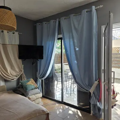 a living room with blue curtains and a sliding glass door at Larnaca Breeze in Pyla