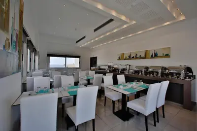a restaurant with white chairs and tables and a counter at The Josephine Boutique Hotel in Larnaka