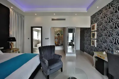 a bedroom with a bed and a chair and a mirror at The Josephine Boutique Hotel in Larnaka