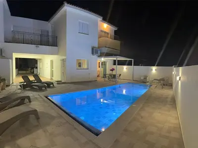 a swimming pool in front of a house at night at Margarita Luxury 3 Bed & Pool in Dherinia