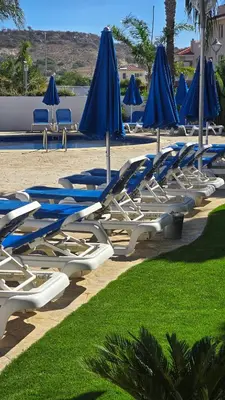 a bunch of lounge chairs with blue umbrellas at Sunny Pyla Escape with Pool, Tennis & Fast Wi-Fi in Pyla