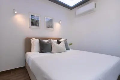 a white bedroom with a large white bed with pillows at Palaiomylos Forest Residence