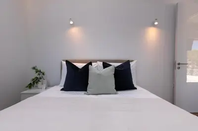 a bedroom with a white bed with blue pillows at Palaiomylos Forest Residence