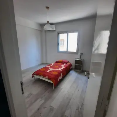 a bedroom with a bed with a red comforter and a window at Modern 3BR Family Apartment in Quiet Drosia with Balcony in Larnaka