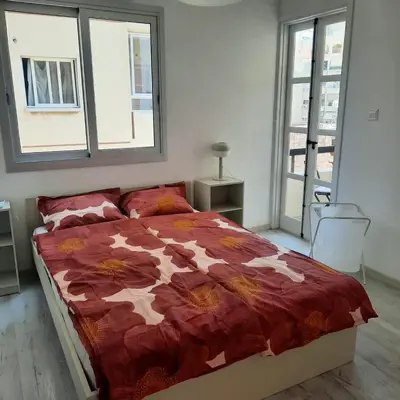 a bedroom with a bed with a red comforter and two windows at Modern 3BR Family Apartment in Quiet Drosia with Balcony in Larnaka